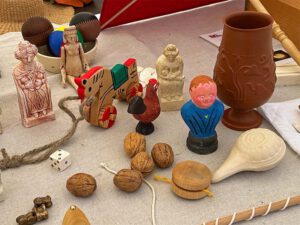 Römisches Spielzeug auf Tisch, unter anderem  Gliederpuppe, Rasseln, Jojo, Astragale aus Bronze.